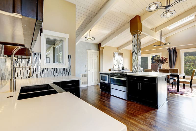 Modern Kitchen With Dark Brown Cabinets Steel Appliances And Kitchen Island With Bar Stools