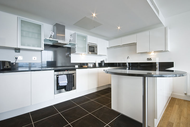 Dark Tile Floor Complements The Black Accent Delivered Through The Countertops In The Kitchen