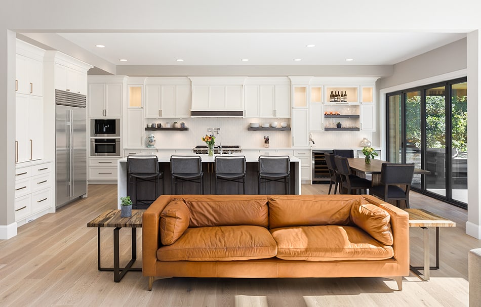 Brown Couch and Black Dining Chairs with Light Hardwood Floors