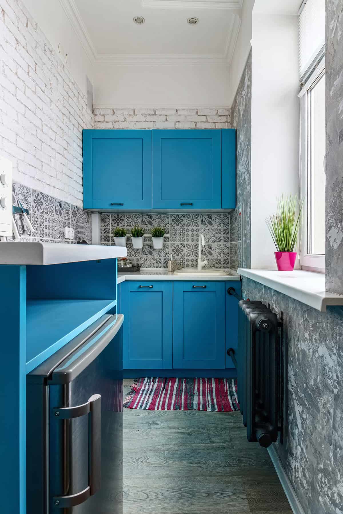 Compact Kitchen with Bold Blue Cabinets and Window Light