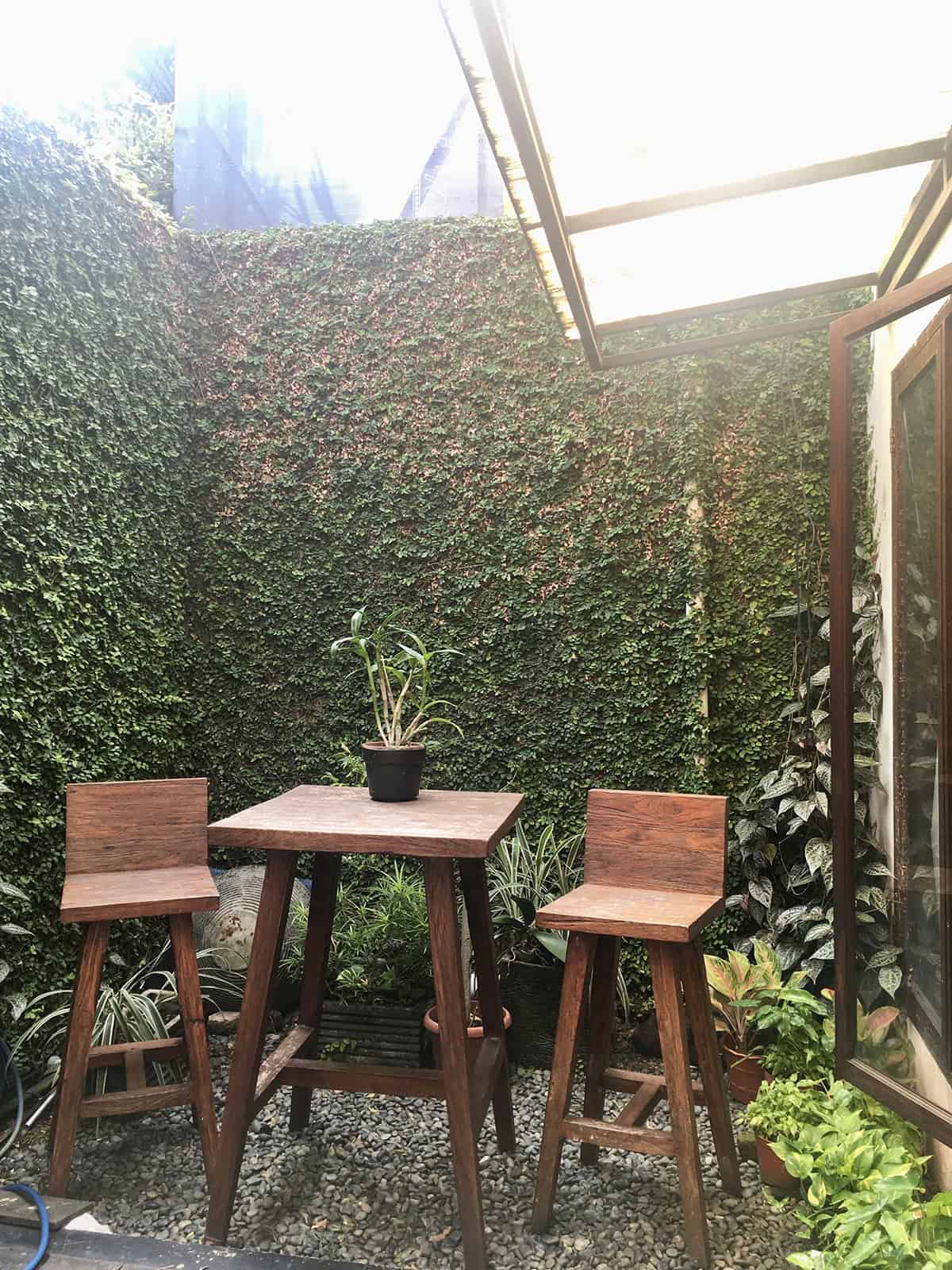 Lush Green Wall Patio with Wooden Bistro Set