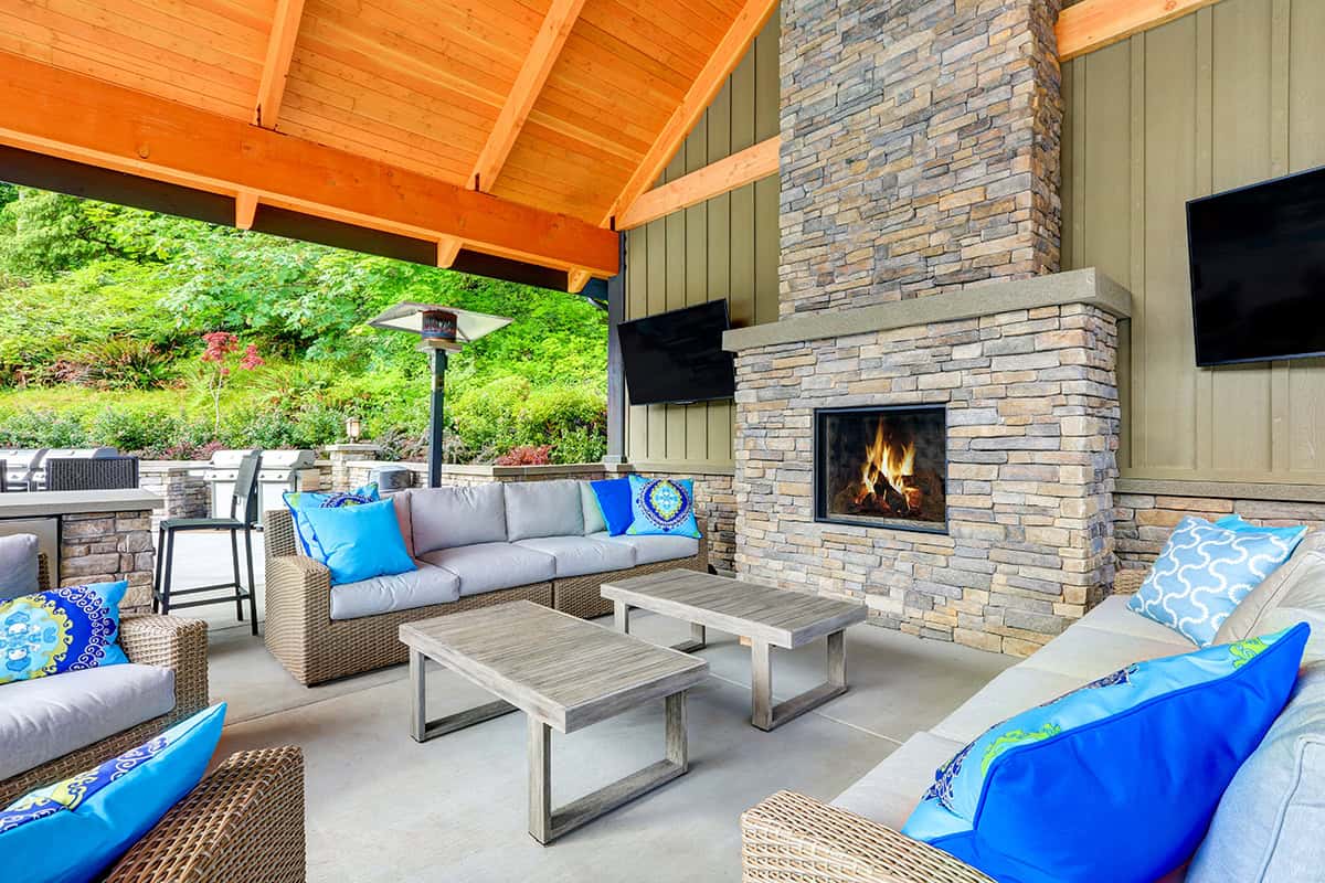 Covered Back Porch with Seating Layout Facing Built In Fireplace